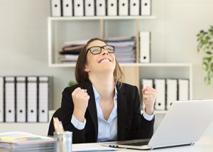 Excited businesswoman celebrating success looking above at office